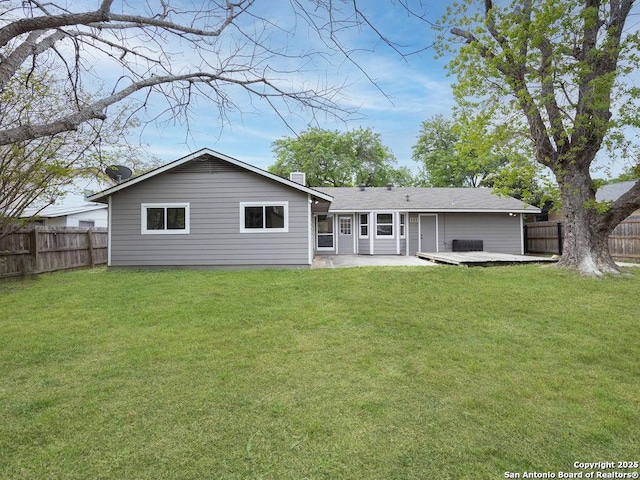 rear view of house with fence, a wooden deck, and a lawn