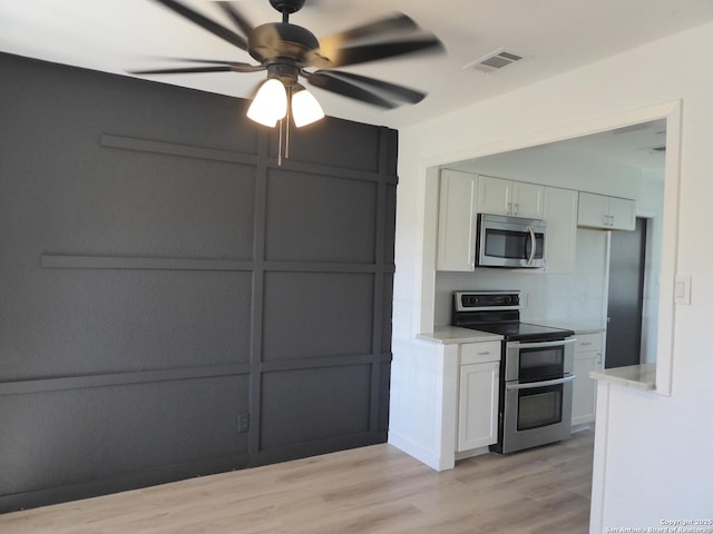 kitchen with stainless steel appliances, light countertops, visible vents, and white cabinetry