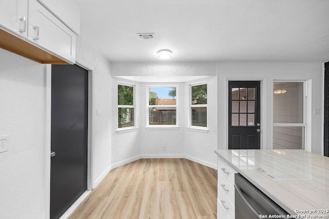 unfurnished dining area with light wood-type flooring, visible vents, and baseboards