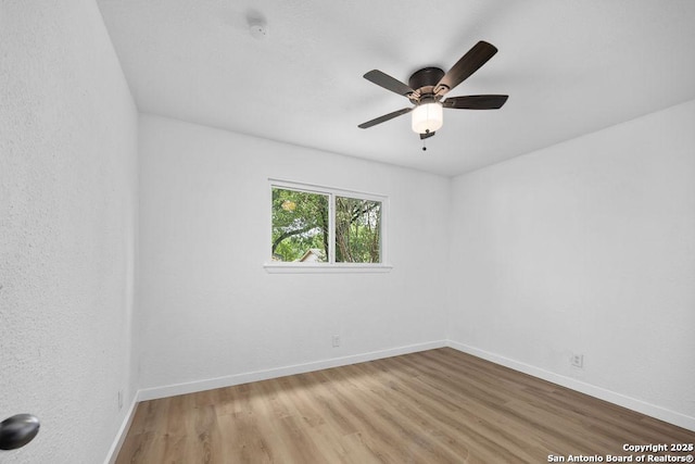 spare room featuring light wood-style floors, ceiling fan, and baseboards