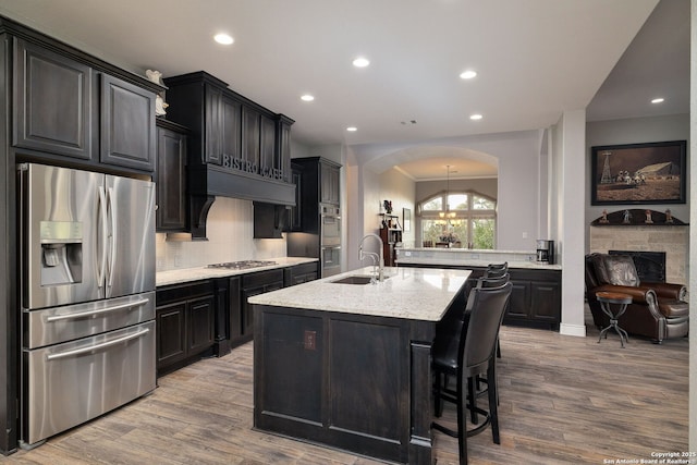 kitchen featuring backsplash, stainless steel appliances, a sink, and wood finished floors