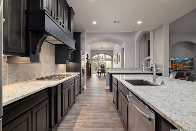 kitchen with tasteful backsplash, visible vents, arched walkways, appliances with stainless steel finishes, and a sink