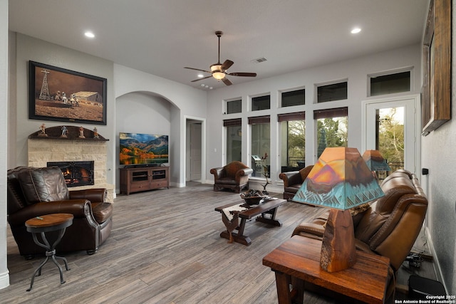 living room with recessed lighting, visible vents, ceiling fan, a stone fireplace, and wood finished floors