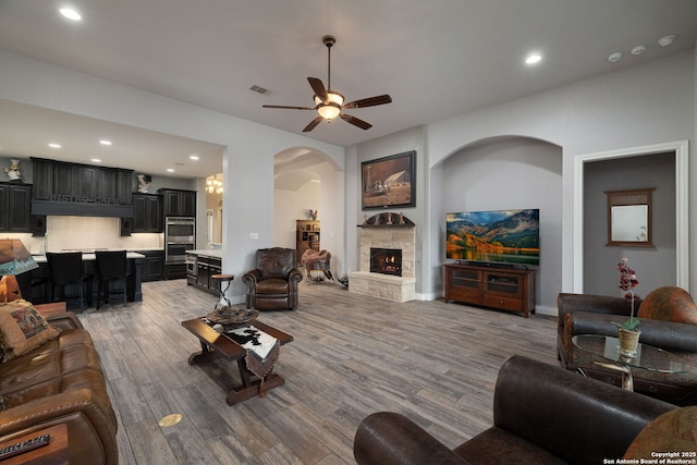 living area featuring ceiling fan, recessed lighting, a fireplace, visible vents, and light wood-style floors