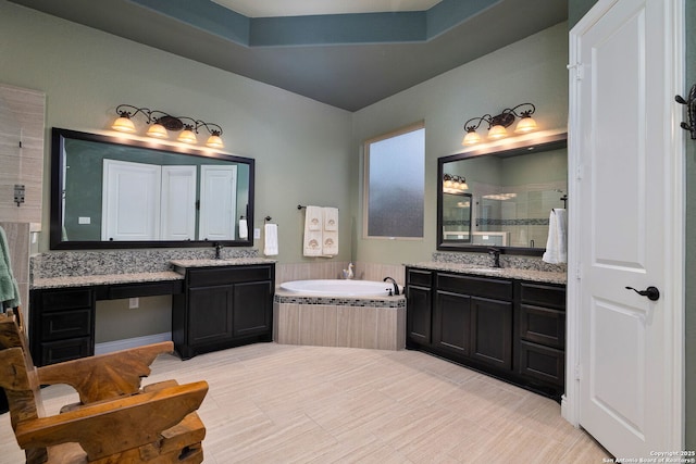 bathroom featuring a garden tub, a shower stall, two vanities, and a sink