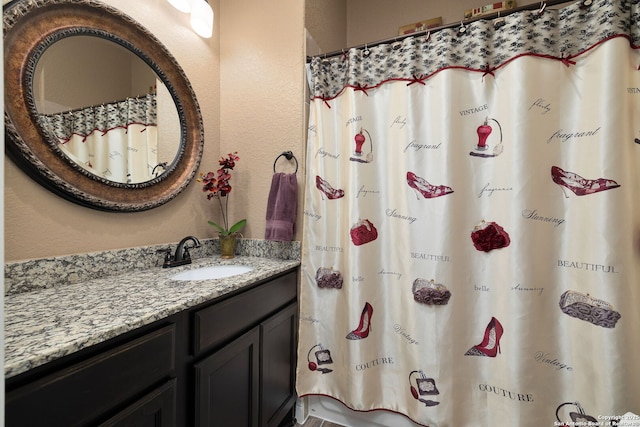 full bathroom with a shower with curtain, a textured wall, and vanity