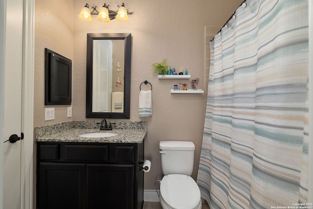 bathroom featuring a textured wall, vanity, and toilet