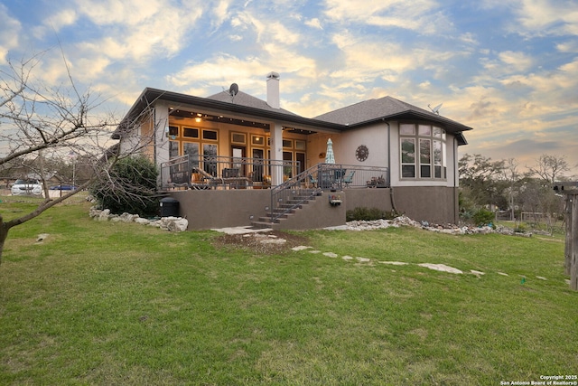 view of front of house featuring a lawn, a chimney, and stucco siding