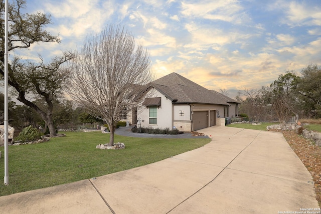 view of front of house with driveway, a shingled roof, a lawn, an attached garage, and stucco siding