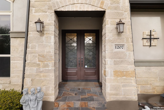 view of exterior entry with stone siding and french doors