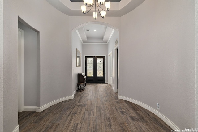 entrance foyer featuring french doors, a tray ceiling, dark wood-style flooring, and baseboards