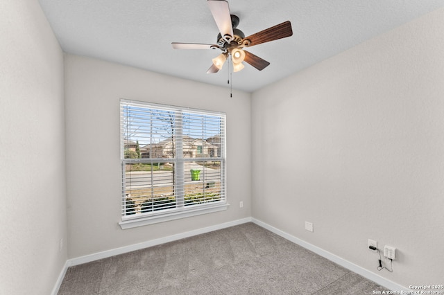 carpeted spare room featuring a textured ceiling, a ceiling fan, and baseboards