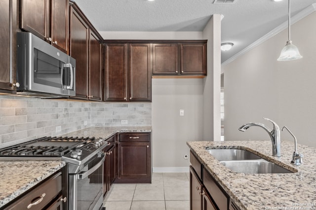 kitchen featuring light stone counters, ornamental molding, decorative light fixtures, stainless steel appliances, and a sink