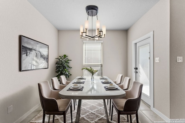 dining space featuring an inviting chandelier, baseboards, and a textured ceiling