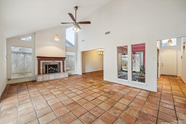 unfurnished living room featuring lofted ceiling, ceiling fan, a fireplace, and tile patterned floors