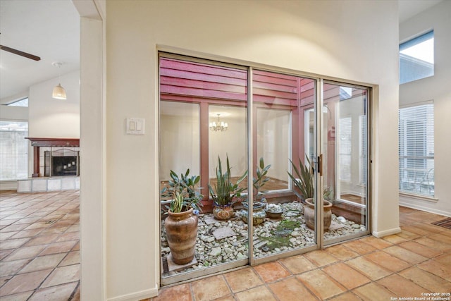 interior space with ceiling fan, high vaulted ceiling, a tiled fireplace, and baseboards