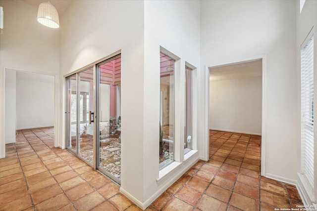 hall featuring a towering ceiling and baseboards