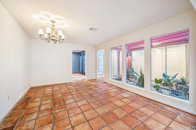 tiled empty room with a textured ceiling, baseboards, visible vents, and a notable chandelier