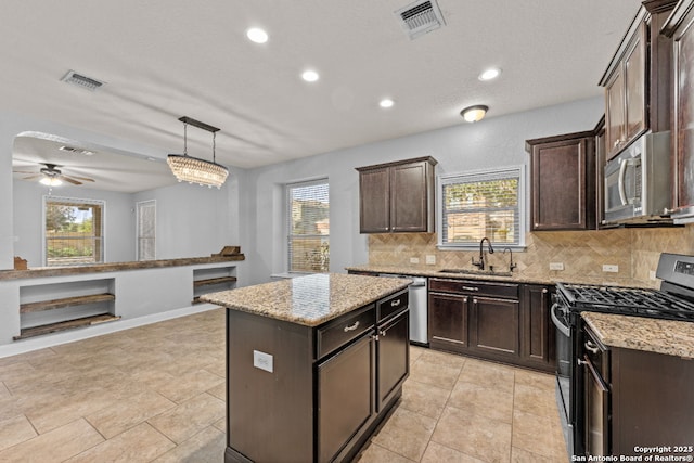 kitchen with dark brown cabinetry, visible vents, decorative backsplash, stainless steel appliances, and a sink