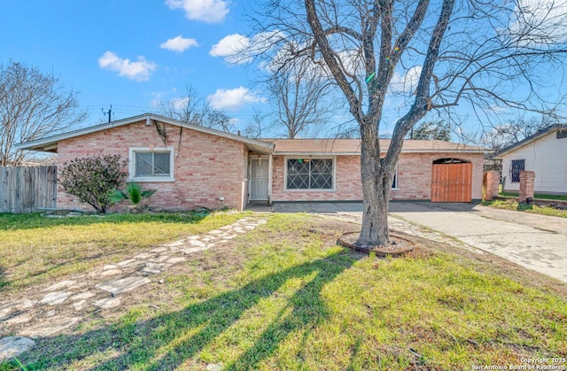 single story home featuring driveway, brick siding, a front yard, and fence