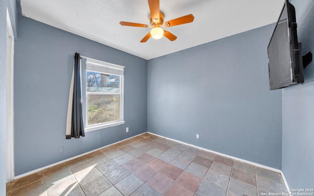 unfurnished room featuring a ceiling fan, stone finish floor, and baseboards