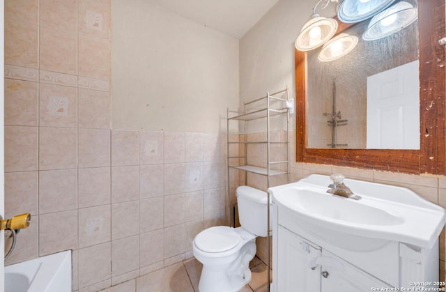 bathroom featuring a bath, tile walls, toilet, and vanity