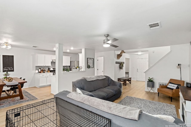 living area with visible vents, ceiling fan, and light wood-style flooring