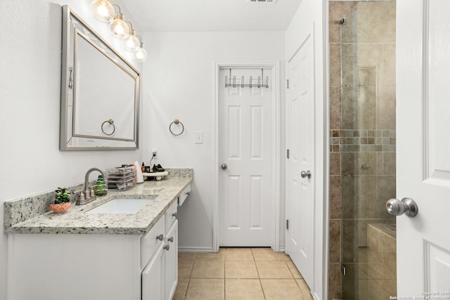 bathroom with vanity, tiled shower, and tile patterned floors