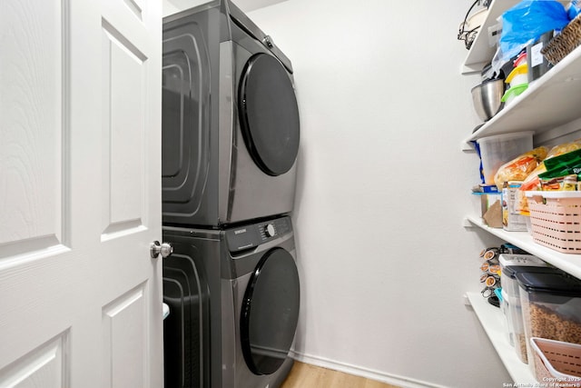 laundry area featuring laundry area, light wood-type flooring, and stacked washing maching and dryer