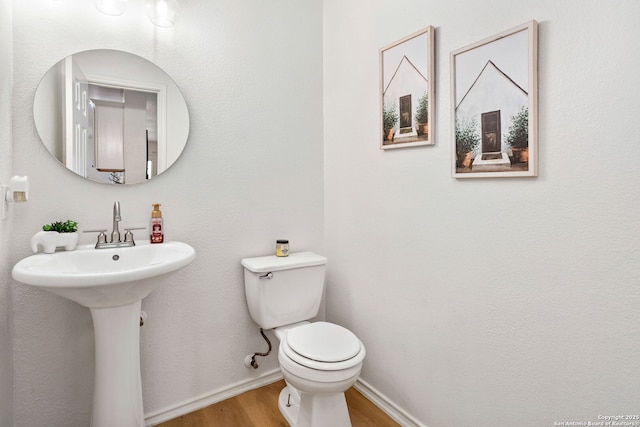 bathroom featuring wood finished floors, toilet, and baseboards