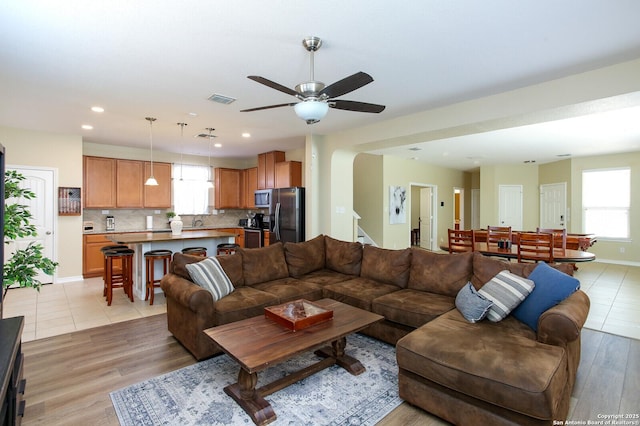 living area with recessed lighting, visible vents, light wood-style flooring, baseboards, and stairs