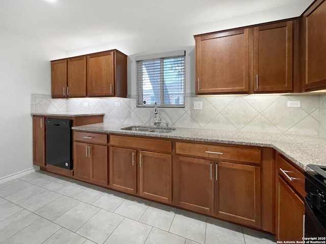 kitchen featuring black appliances, tasteful backsplash, light stone counters, and a sink