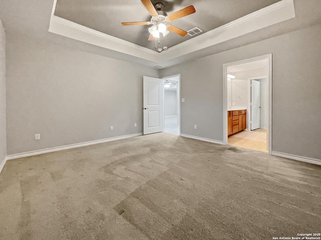 unfurnished bedroom with light carpet, baseboards, and a raised ceiling