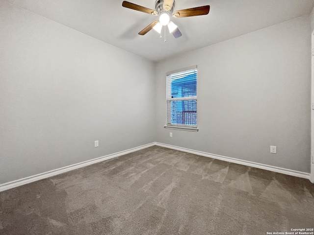 carpeted spare room featuring baseboards and a ceiling fan