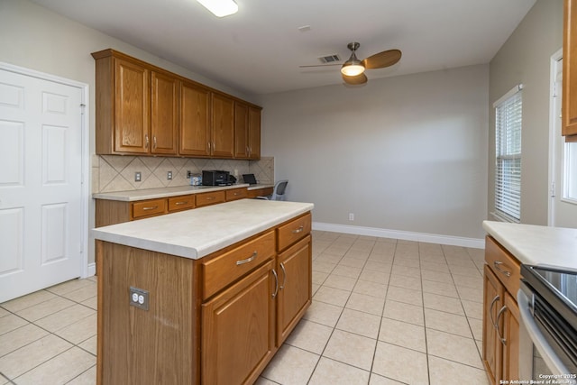 kitchen featuring light tile patterned floors, visible vents, brown cabinetry, decorative backsplash, and light countertops