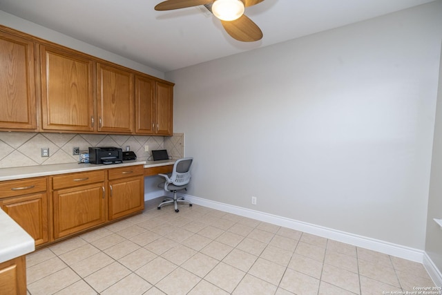 office area with a ceiling fan, built in desk, baseboards, and light tile patterned floors