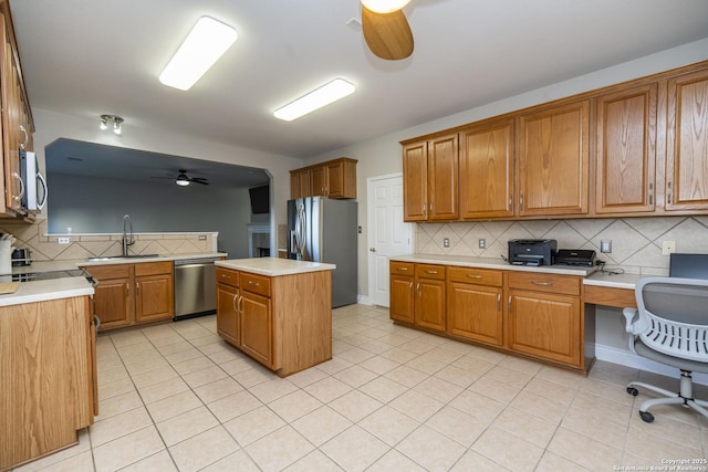 kitchen with brown cabinets, a ceiling fan, stainless steel appliances, and a sink