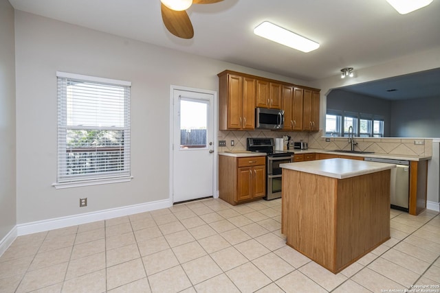 kitchen with light tile patterned floors, a sink, light countertops, appliances with stainless steel finishes, and tasteful backsplash