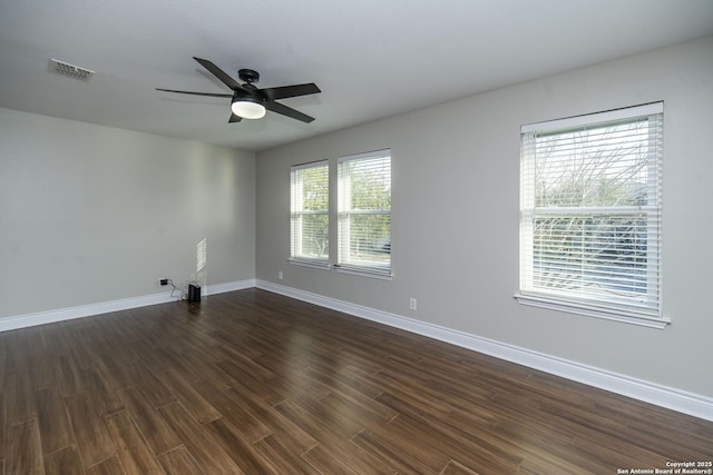 unfurnished room with dark wood-style flooring, visible vents, ceiling fan, and baseboards