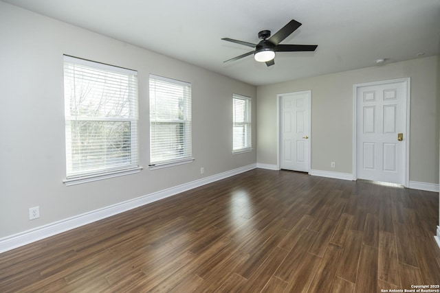 spare room with dark wood-type flooring, a ceiling fan, and baseboards