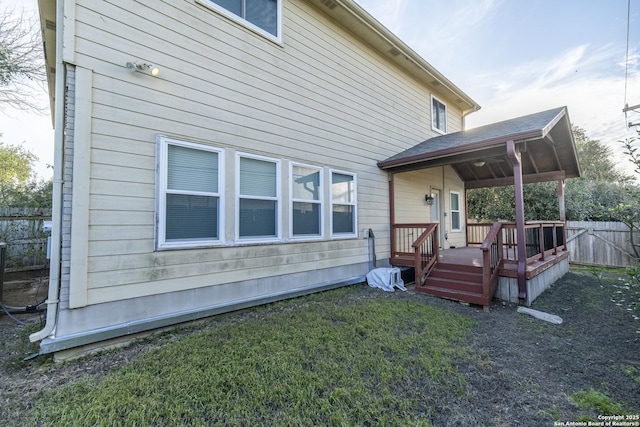 back of property featuring a lawn, fence, and a wooden deck