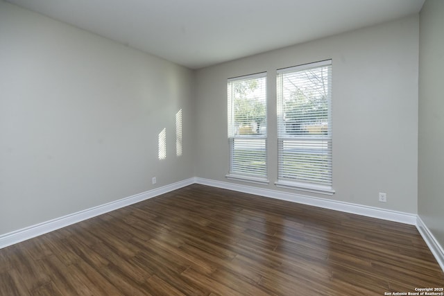 empty room with baseboards and dark wood-type flooring