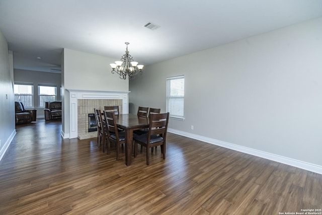 dining space with a brick fireplace, dark wood-style flooring, visible vents, and baseboards