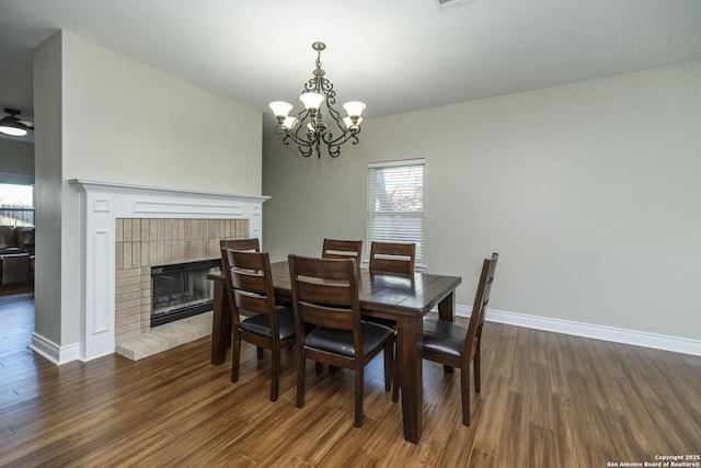 dining room with a brick fireplace, baseboards, a chandelier, and dark wood-style flooring