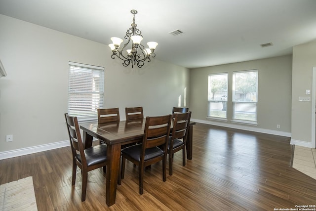 dining area with an inviting chandelier, visible vents, baseboards, and wood finished floors