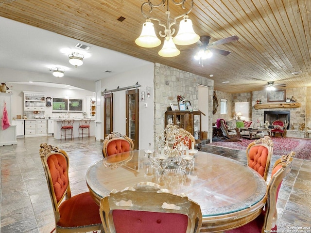 dining space with wooden ceiling, ceiling fan, visible vents, and a stone fireplace