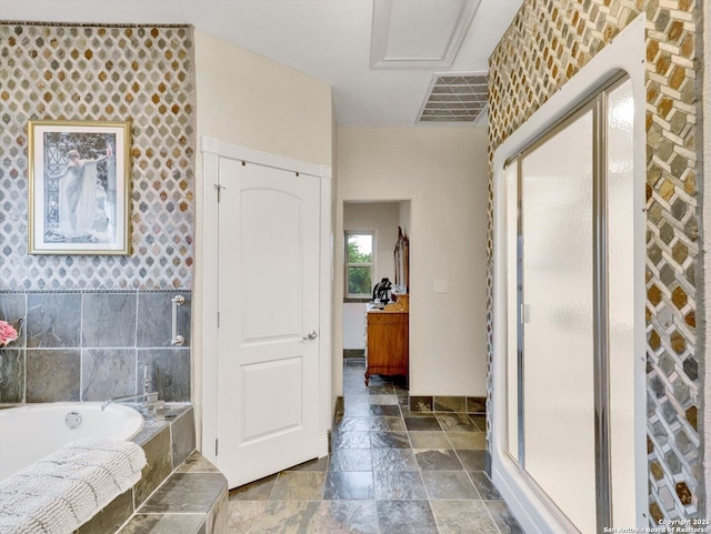 bathroom featuring a stall shower, visible vents, a garden tub, and stone tile flooring