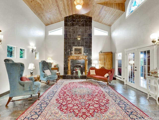 living area with a tiled fireplace, wooden ceiling, stone tile floors, and french doors