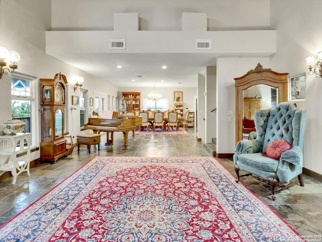 living area with baseboards, a high ceiling, visible vents, and an inviting chandelier