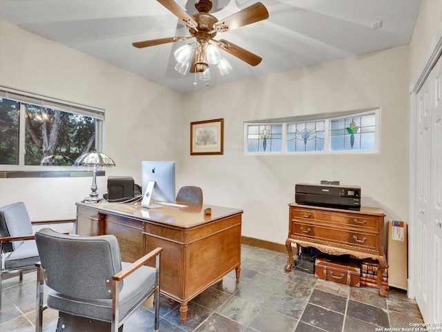 office featuring stone finish flooring, baseboards, and a ceiling fan